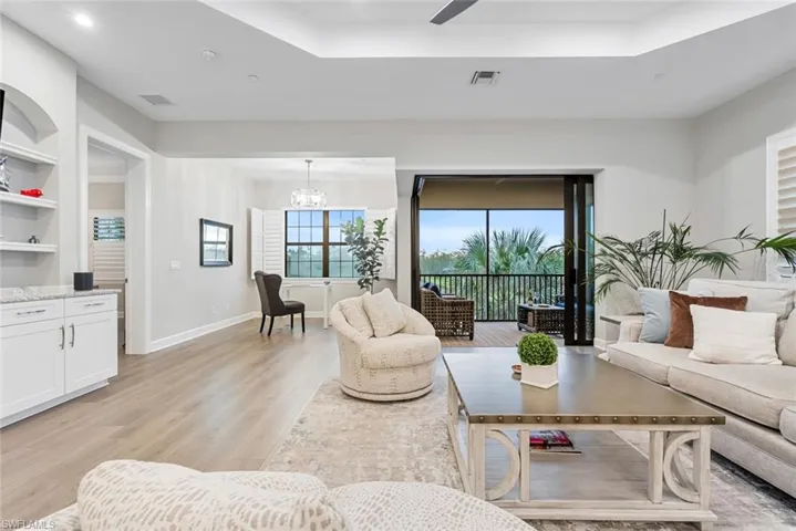 Living room featuring a tray ceiling, light hardwood / wood-style flooring, and a notable chandelier