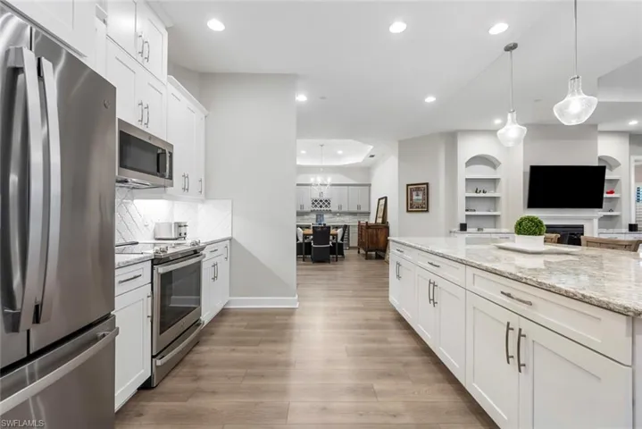 Kitchen with light hardwood / wood-style floors, white cabinetry, pendant lighting, and stainless steel appliances