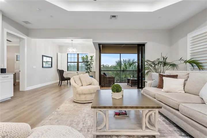 Living room featuring light wood-type flooring, an inviting chandelier, and a wealth of natural light