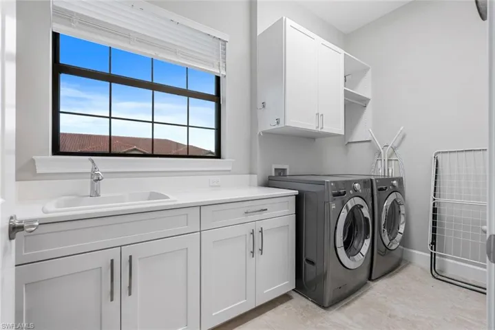 Washroom featuring cabinets, sink, and washing machine and dryer