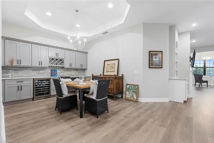 Dining space featuring light hardwood / wood-style floors, a tray ceiling, wine cooler, and a notable chandelier