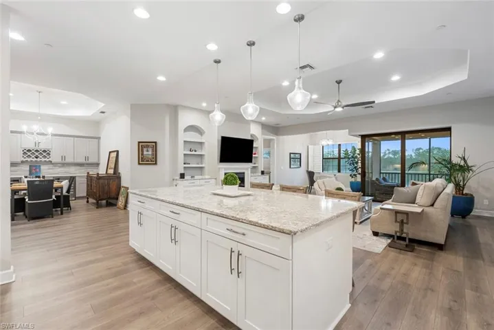 Kitchen with white cabinets, decorative light fixtures, a center island, and light wood-type flooring