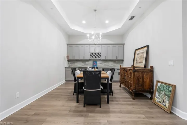 Dining space with an inviting chandelier, a tray ceiling, and light hardwood / wood-style floors