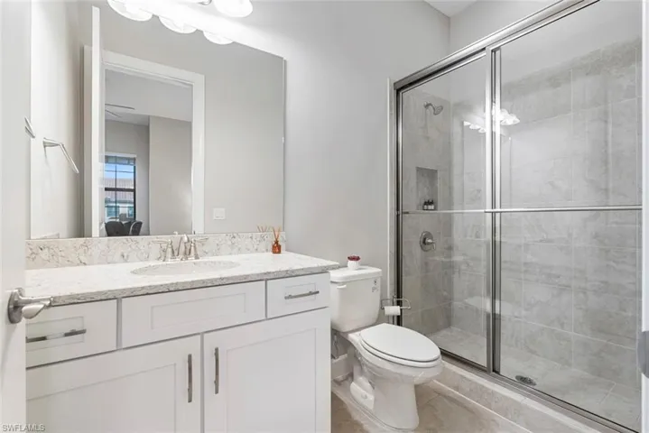 Bathroom featuring walk in shower, vanity, and toilet