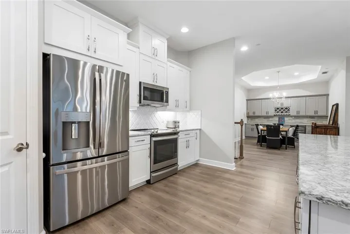 Kitchen with light hardwood / wood-style flooring, appliances with stainless steel finishes, backsplash, and white cabinetry