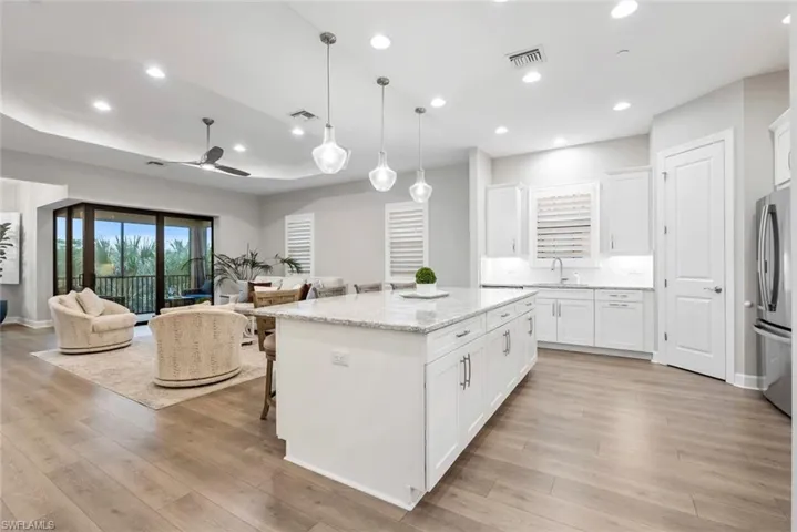 Kitchen featuring light wood-type flooring, stainless steel fridge, a kitchen island, and white cabinets