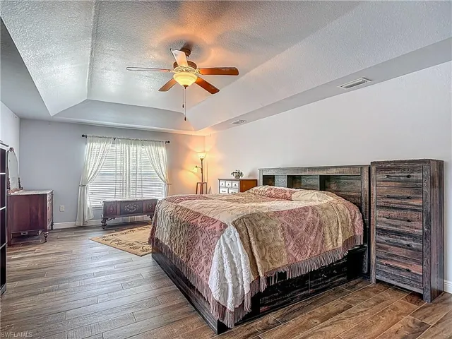 Spacious primary bedroom with freshly painted walls, volume ceiling