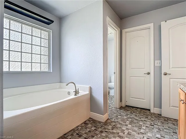 Ensuite bath soaking tub with view of private toilet room.