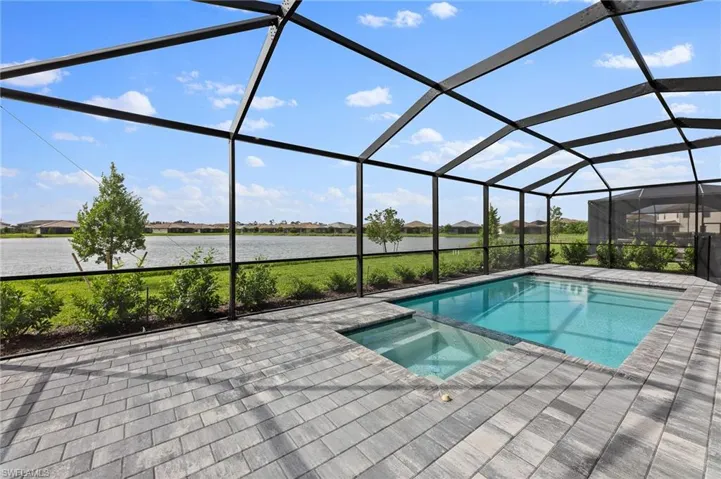 Integrated pool / hot tub featuring a sunroom, a residential view, glass enclosure, and a water view