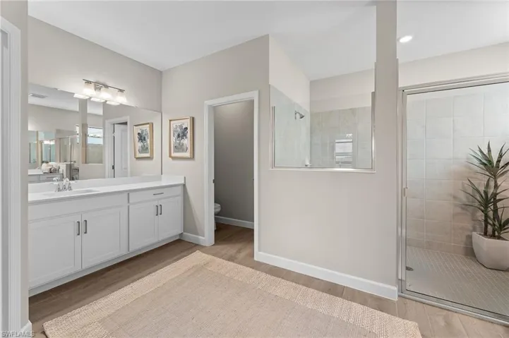 Full bathroom featuring a stall shower, vanity, and light wood-type flooring