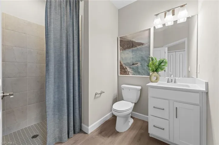 Full bathroom with a stall shower, vanity, and light wood-style floors