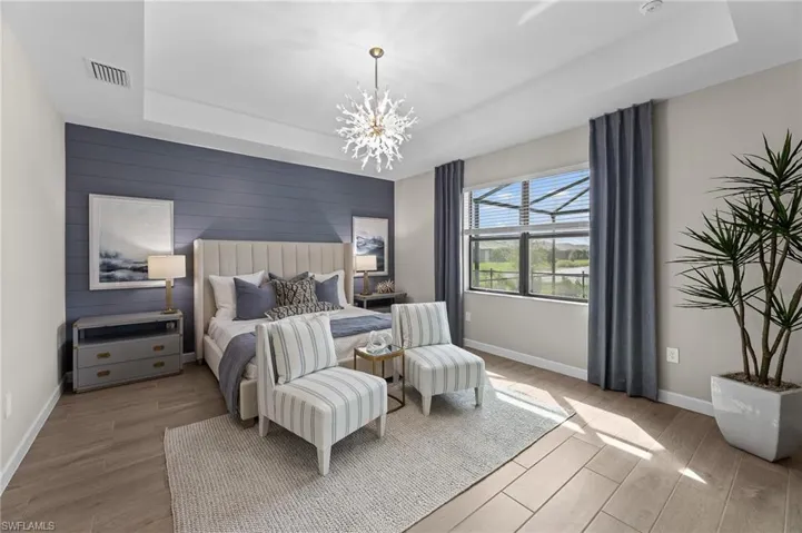 Bedroom with an accent wall, wood tiled floors, a raised ceiling, hanging lights, and wooden walls