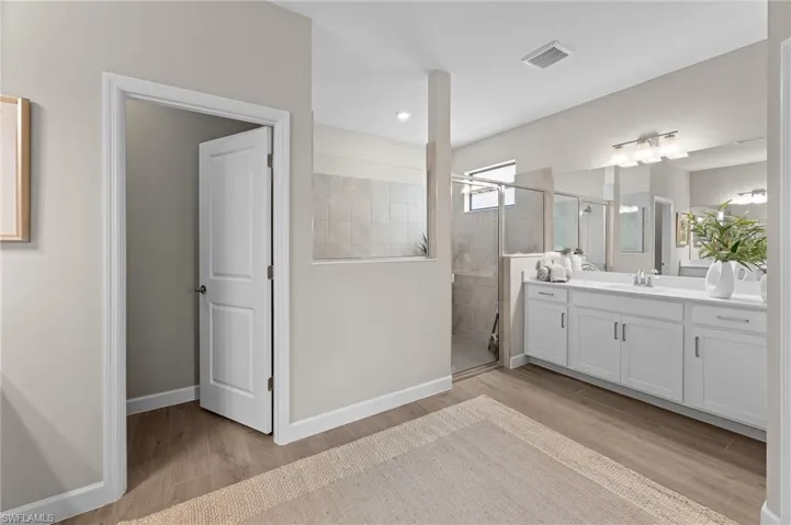 Bathroom featuring a shower stall, vanity, and light wood-style floors