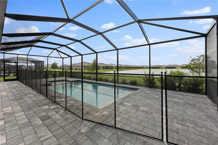Swimming pool with a sunroom, a residential view, glass enclosure, and a patio