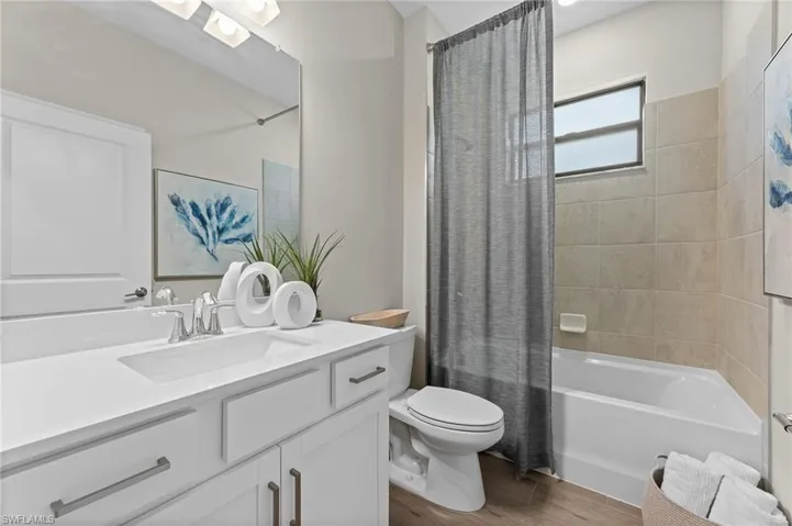 Bathroom featuring shower / tub combo, vanity, and light wood finished floors