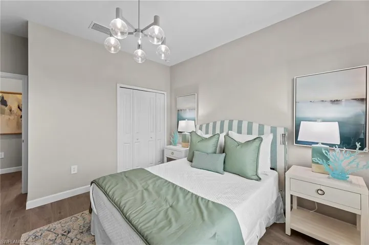 Bedroom with wood finished floors, a closet, and hanging lights