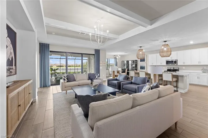 Living room featuring light wood finished floors, hanging lights, plenty of natural light, and beam ceiling