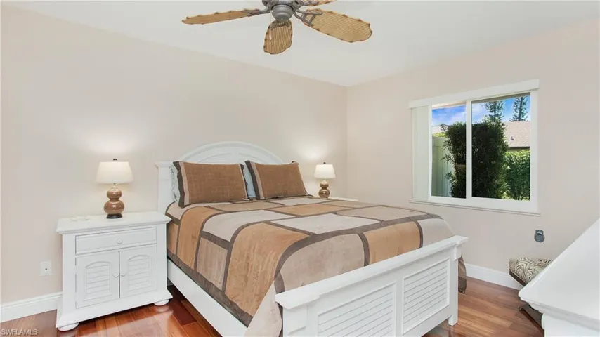 Guest Bedroom #1 with ceiling fan, 5" baseboards, and wood floors