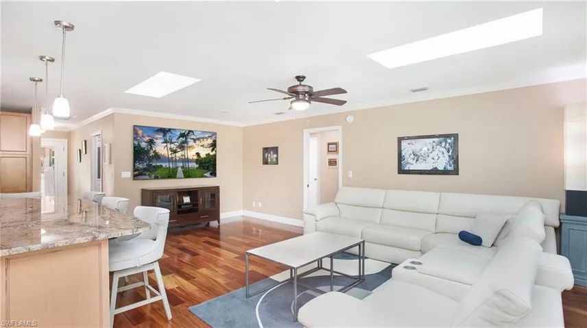 Living room with ornamental molding, a skylight, visible vents, and wood finished floors