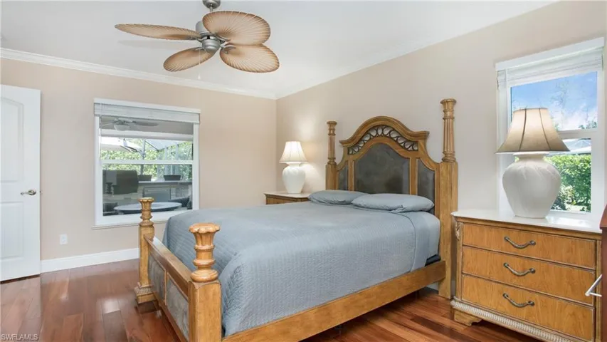 Primary Bedroom with large window, Crown molding, ceiling fan, and wood flooring