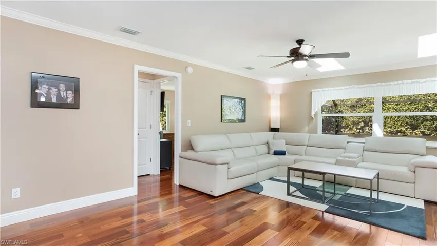 Living area with visible vents, crown molding, baseboards, and wood finished floors