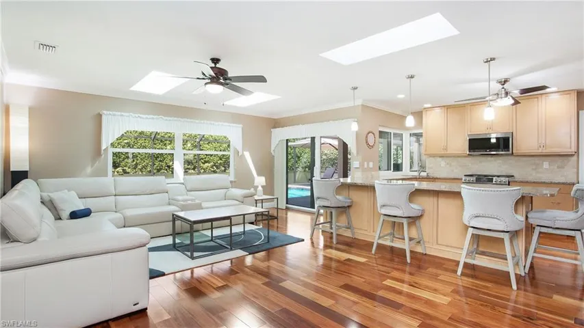 Living area featuring a skylight, visible vents, a ceiling fan, light wood-style floors, and ornamental molding