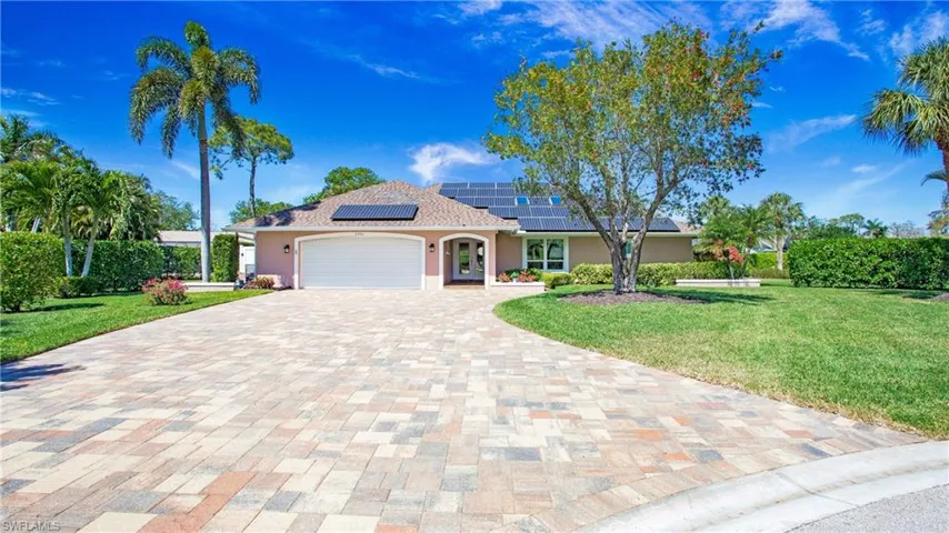 View of front featuring a 2 car garage, Paver Stone driveway, roof mounted solar panels and front lawn