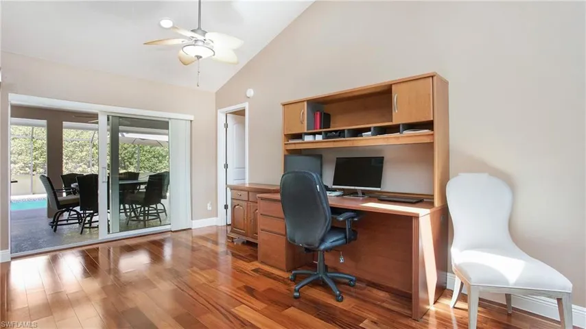 Office area with high vaulted ceiling, sliding glass doors, 5" baseboards, ceiling fan, and wood floors. This room has the potential to be a separate enclosed office with sliding glass doors.