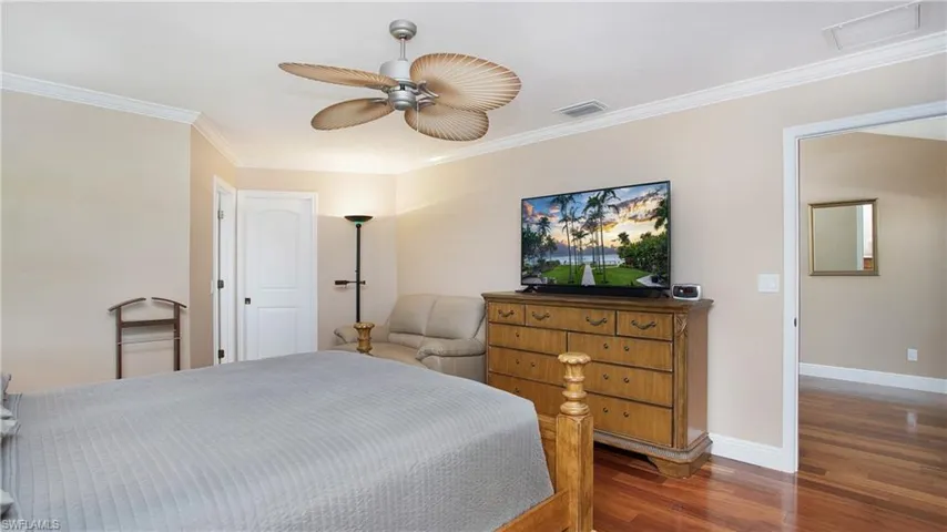 Primary Bedroom with Crown molding, 5" baseboards, and wood floors