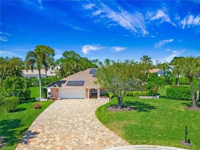 View of front of house featuring a garage, solar panels, paver stone driveway, and front lawn