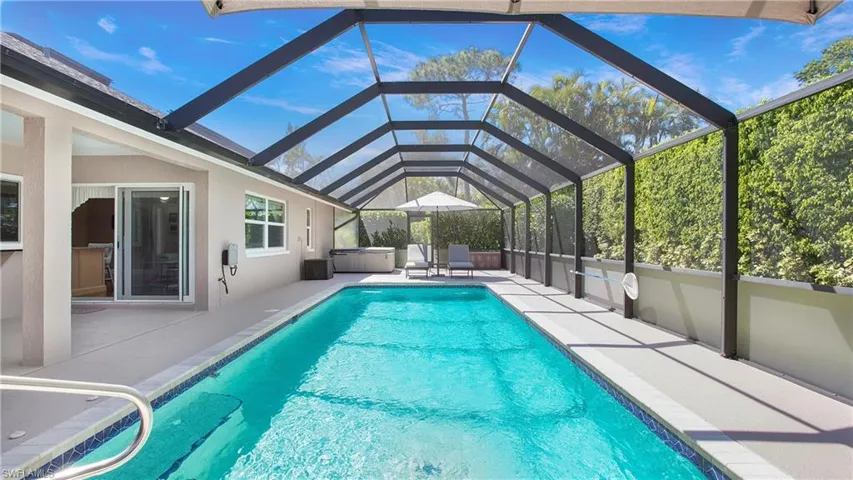View of screened in swimming pool with spa/hot tub