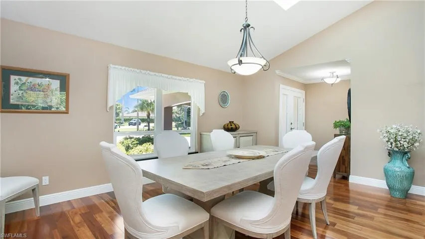 Dining area featuring vaulted ceiling, wood flooring, large window and 2 skylights