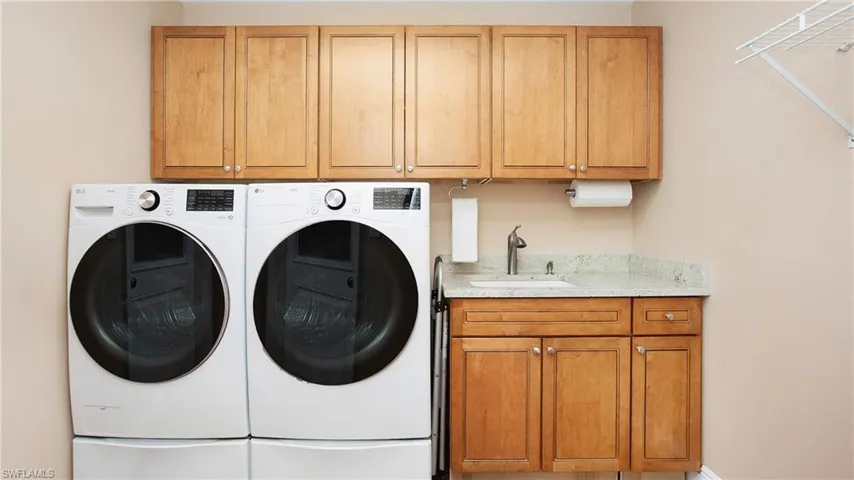 Laundry room featuring front load washer and dryer, cabinet space for storage, and sink