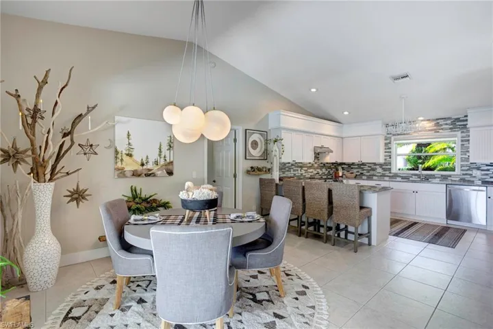 Tiled dining room featuring vaulted ceiling and sink
