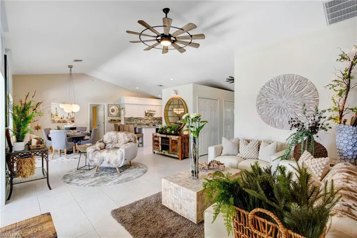 Living room featuring lofted ceiling, ceiling fan, and light tile floors