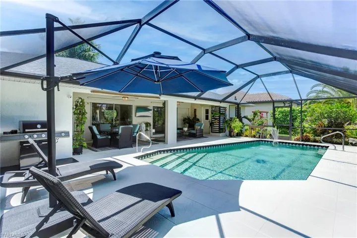 View of swimming pool with glass enclosure and a patio area