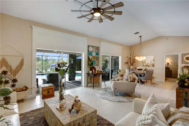 Tiled living room featuring ceiling fan and vaulted ceiling