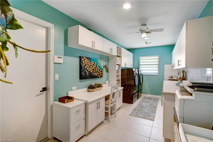 Kitchen featuring washer and dryer, white cabinetry, backsplash, light tile flooring, and ceiling fan