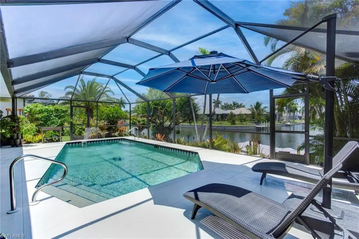 View of swimming pool with screened enclosure, a water view, and a patio area