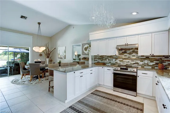 Kitchen featuring kitchen peninsula, pendant lighting, backsplash, light tile floors, and stainless steel electric stove