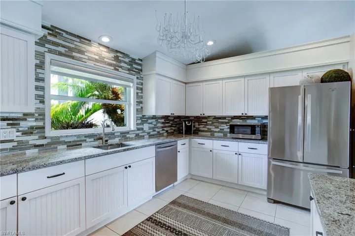 Kitchen with light stone counters, backsplash, light tile floors, and appliances with stainless steel finishes