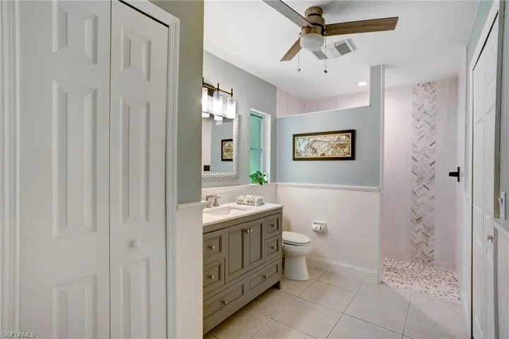 Bathroom featuring tile flooring, ceiling fan, toilet, and large vanity