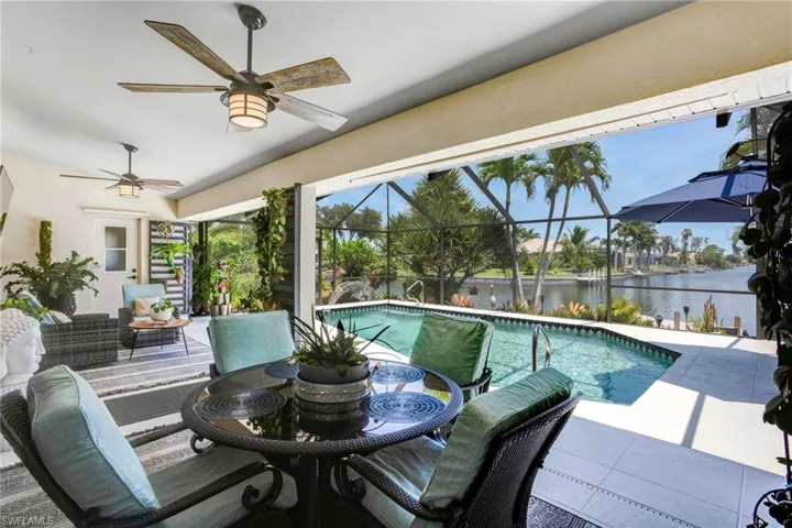 View of swimming pool with a patio, a water view, an outdoor living space, glass enclosure, and ceiling fan
