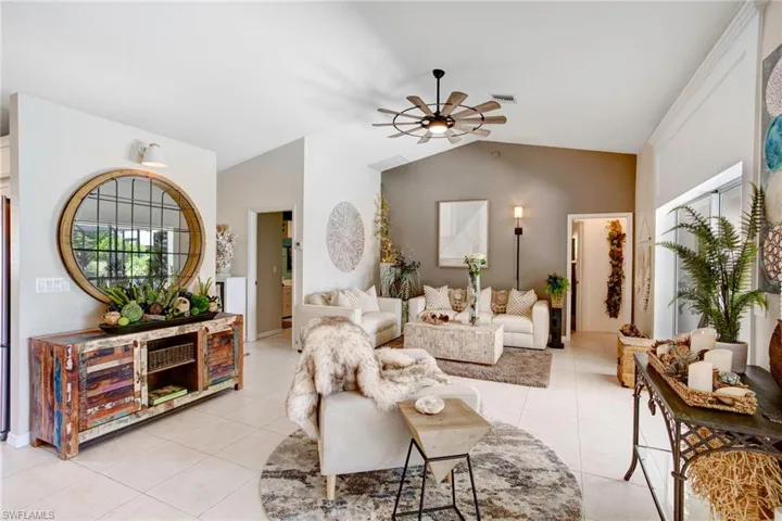 Tiled living room featuring ceiling fan and vaulted ceiling