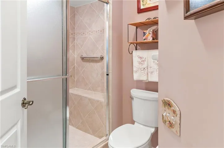 Primary bathroom with toilet and seat in shower