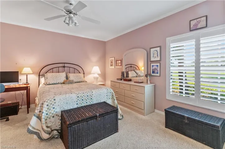 Bedroom featuring baseboards, carpet flooring, ornamental molding, and ceiling fan