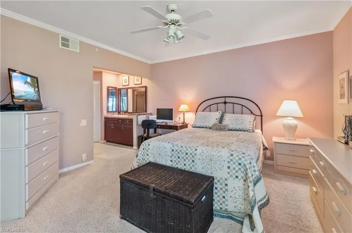 Bedroom featuring a ceiling fan, crown molding, light carpet, baseboards, and visible vanity
