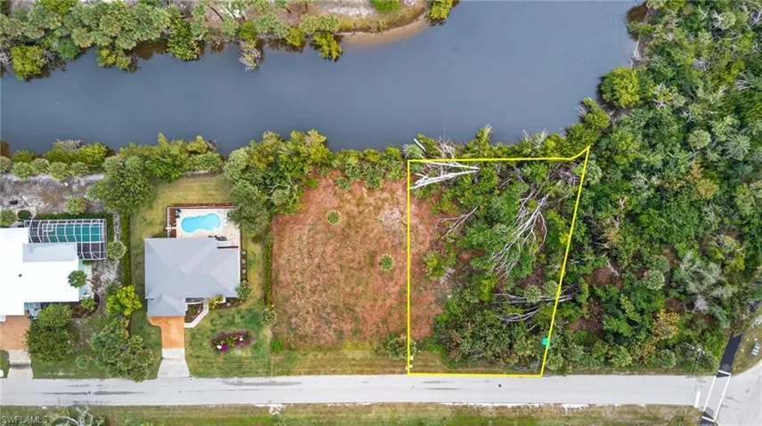 Aerial view of property and surrounding area with property parcel outlined and a nearby body of water