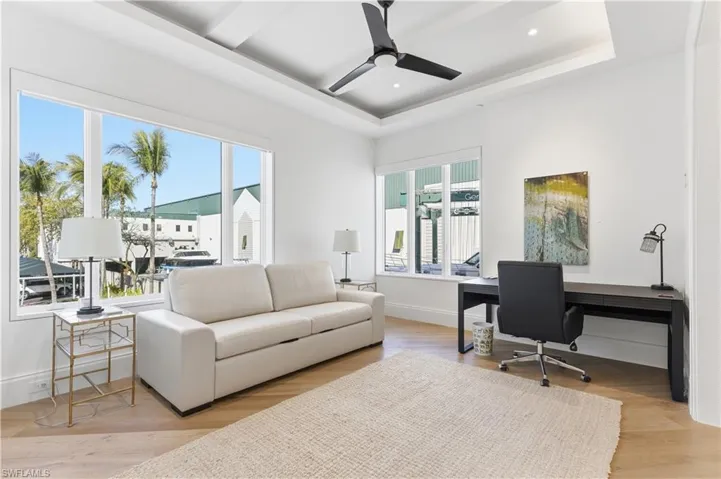 Office space featuring light wood-type flooring, ceiling fan, a raised ceiling, and recessed lighting