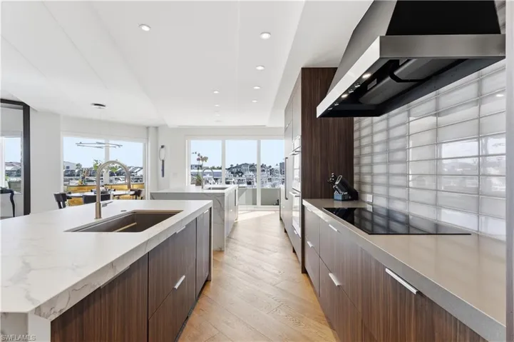 Kitchen with modern cabinets, light wood-style floors, black electric cooktop, light stone countertops, and dual tone cabinets
